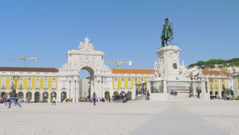 A-long-view-of-The-Rua-Augusta-Arch-historical-building-and-visitor-with-Statue-of-King-José-I-The-king-on-his-horse-crushing-snakes-on-his-path,-Lisbon,-Portugal
