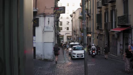 Naples,-Italy,-Busy-Traffic-in-Small-Street-Between-Old-Buildings-and-People-on-Sidewalk