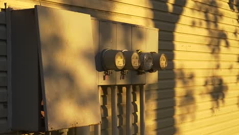 Hydro-panel-box-and-round-meters-on-end-of-multi-residential-townhouse-development-with-shadow-of-tree