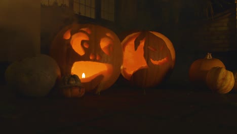 2-carved-lit-pumpkin-outside-the-front-of-a-house-Halloween-with-smoke-with-little-pumpkins