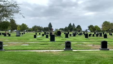 Pan-view,-cemetery-gravesite-with-headstones,-on-a-cloudy-day-in-Los-Angeles