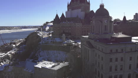 Majestic-Chateau-Frontenac-sits-covered-in-snow-on-Hilltop,-Drone-Aerial