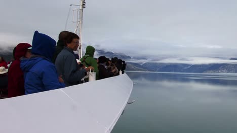 Tourists-enjoying-the-scenery-in-the-Glacier-Bay-National-Park,-Alaska-from-the-bow-of-the-cruise-ship