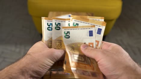 Manos-Contando-Nuevos-Billetes-De-Cincuenta-Euros,-Pila-De-Dinero-En-Segundo-Plano,-Cerrar
