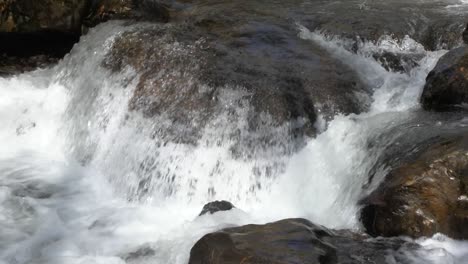 Clear-mountain-stream-flows-over-smooth-river-rock-in-small-waterfall,-60fps