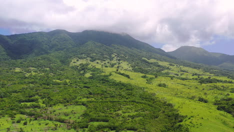 Exotic-tropical-landscape-of-the-island-of-Saint-Kitts,-West-Indies,-in-the-Caribbean-sea,-with-green-plains-and-forests,-tall-mountains-covered-with-trees,-large-clouds-above