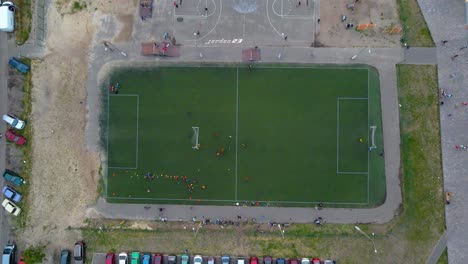 Aerial-view-above-a-soccer-field,-teams-playing-football,-in-a-poor,-slum-neighborhood-of-Kyiv,-cloudy-day,-in-Kiev,-Ukraine---top-down,-drone-shot