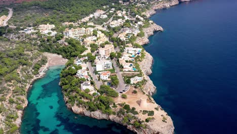 Seaside-town-of-Torrent-de-Cala-Pi-with-beach-inlet-near-by-on-Mallorca-Spain,-Aerial-dolly-out-shot