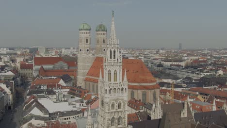 Aerial-View-of-Munich-New-City-Hall-aka-Rathaus,-Frauenkiche-Catholic-Cathedral-at-Marienplatz,-Historic-Downtown-Square,-Descending-Drone-Shot