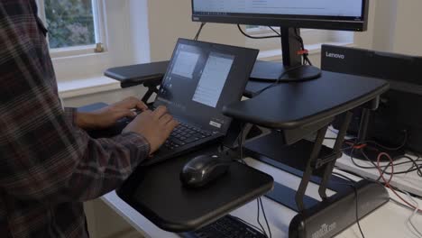 Adult-Male-Using-Laptop-On-Ergonomic-Standing-Desk-In-Office