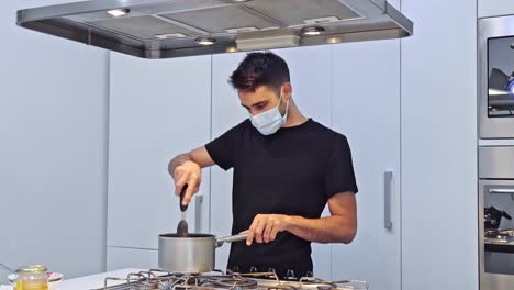 Young-man-is-cooking-food-for-delivery-in-his-restaurant-in-protective-mask