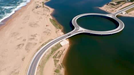 Drone-capturing-car-approaching-the-bridge-in-the-ocean-in-Garzon,-Maldonado,-Uruguay