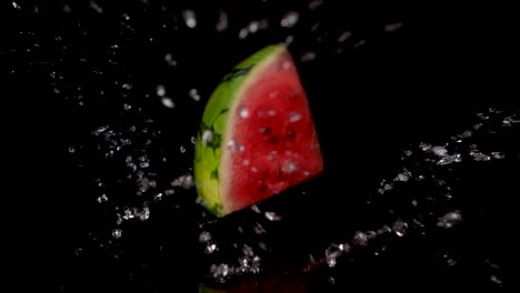 Slow-motion-shot-of-falling-piece-of-watermelon-on-wet-surface-with-black-background