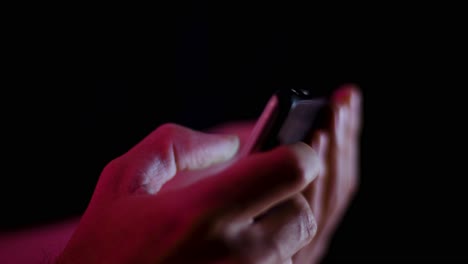Thumb-on-a-smartphone-while-a-video-plays-in-landscape-close-up-in-a-dark-room-side-profile