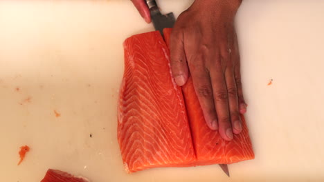 Chef-Cutting-The-Salmon-Meat-Fillet-In-Half-And-Separating-From-Its-Skin-For-Sushi-Dish
