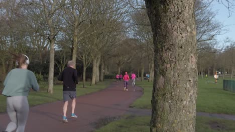 Active-fitness-group-jogging-and-walking-in-wet-rainy-park-in-slow-motion-parallax-tree