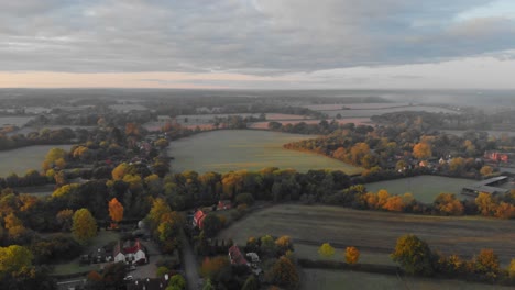 dolly-forward-drone-shot-over-the-green-English-countryside-fields-early-morning-golden-hour