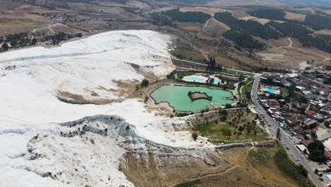 Drone-footage-of-a-small-lake-against-the-backdrop-of-white-rocks-in-the-Pamukkale-region-of-Turkey-near-the-city-and-the-road