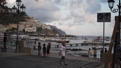 Ciudad-De-Amalfi,-Italia,-Niños-Jugando-Al-Fútbol-Junto-Al-Mar-Mediterráneo-Y-El-Puerto-De-La-Ciudad