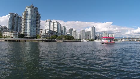 Half-empty-with-passengers,-a-water-taxi-passes-by-false-creek-yaletown-harbor-with-hardly-any-other-boats-out-at-the-waterfront-residential-condominium-quay-community-of-downtown-Vancouver-Canada-1-2