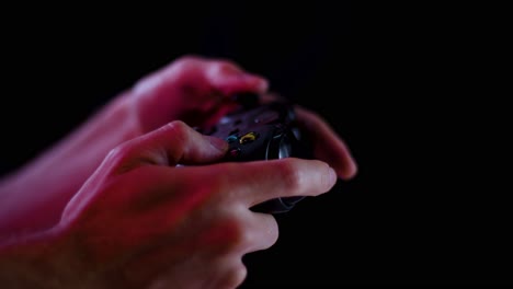 Playing-video-games-in-a-darkened-room-with-a-black-background-close-up-on-a-controller-buttons-playing-slowly-for-e-sports