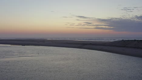 Drone-Flies-into-Beautiful-Sunset-Over-Shoreline-and-beachhead-along-the-Atlantic-coast-of-Fuseta,-Aerial