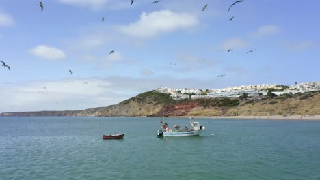 Fischerboot-Fährt-In-Richtung-Salema-Strand-In-Portugal,-Während-An-Einem-Sonnigen-Und-Schönen-Tag-Hungrige-Möwen-über-Uns-Hinwegfliegen