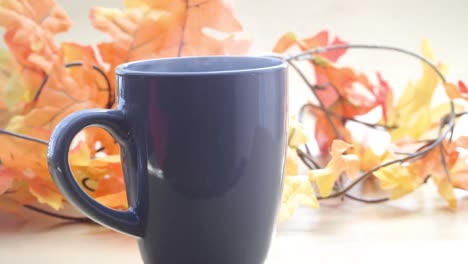 Aus-Einer-Tasse-Kaffee-Oder-Tee-Aufsteigender-Dampf-Mit-Bokeh-Effekt-Und-Goldenen-Blättern