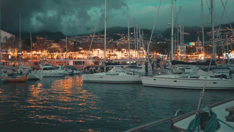 Back-view-of-sailor-sailing-toward-Madeira-Marina-yacht-club-at-evening