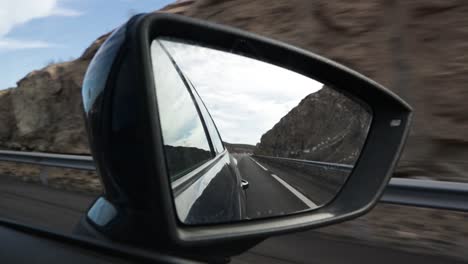 Car-side-rear-mirror-view-of-an-empty-road-on-the-motorway