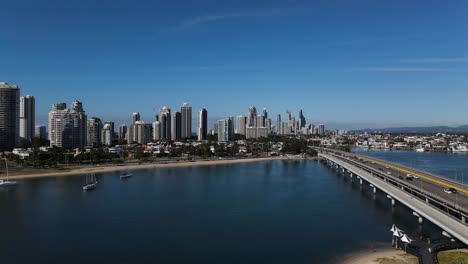A-moving-high-view-following-a-busy-road-and-bridge-entering-into-a-city-full-of-high-rise-buildings-surrounded-by-water
