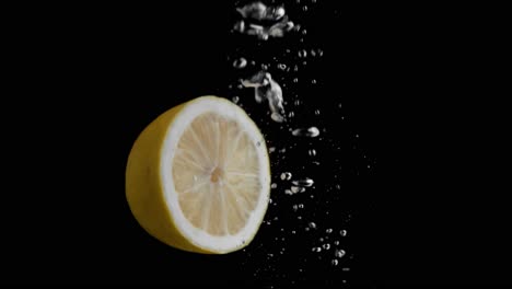 Zitrone-Fällt-Ins-Wasser-Super-Slowmotion,-Schwarzer-Hintergrund,-Viele-Luftblasen,-4k240fps