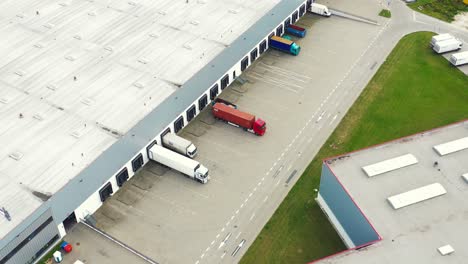 Logistics-park-with-warehouses,-loading-hub-and-a-lot-of-semi-trailer-trucks-waits-for-load-and-unload-goods-at-ramps
