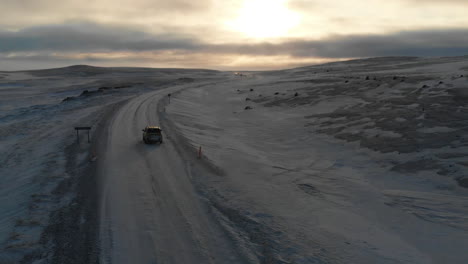 Aerial-View,-Car-on-Icy-Road-in-Highland-of-Iceland-With-Stunning-Sky-on-Horizon-,-Cinematic-Drone-Shot