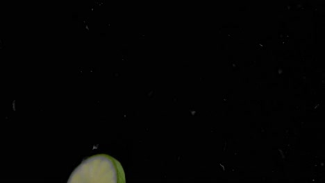 Lime-Slice-Falling-into-Water-Super-Slowmotion,-Black-Background,-lots-of-Air-Bubbles,-4k240fps