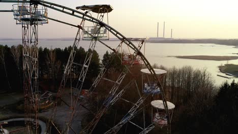 Old-abandoned-ferris-wheel-carousel-in-front-of-power-plant-chimneys