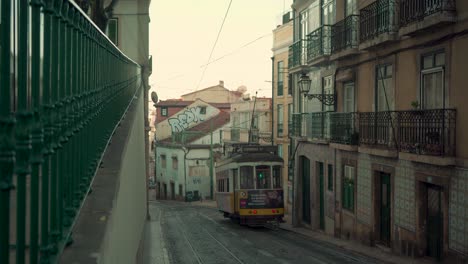Lisbon-Alfama-ancient-medieval-vintage-street-in-stone-pavement,-houses-roofs,-railway-tram-passing-by-4K