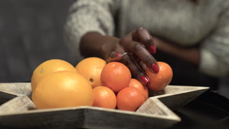 Mujer-Negra-Recogiendo-Mandarina,-Naranjas-De-Un-Tazón