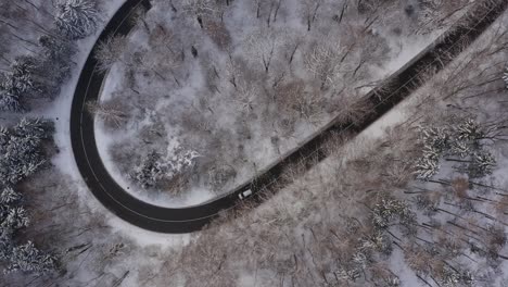 Verschneite-Luftaufnahme-Von-Der-Kurvenreichen-Straße-Mit-Einem-Fahrenden-Auto-Hinauf-Zum-Tourismus-Hotspot-Monster-Schäftlarn,-Eingebettet-In-Eine-Wunderschöne-Winterlandschaft-Mit-Den-Alpen-Im-Hintergrund