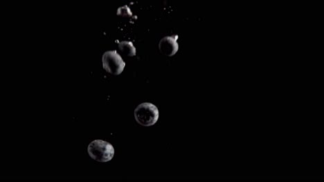 Currants-Falling-into-Water-Super-Slowmotion,-Black-Background,-lots-of-Air-Bubbles,-4k240fps