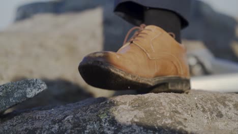 Close-shot-of-a-brown-stylish-shoe-on-a-rock