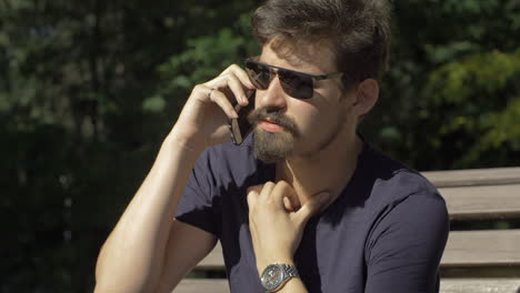 Male-talking-cellphone-along-park-slow-motion-beard