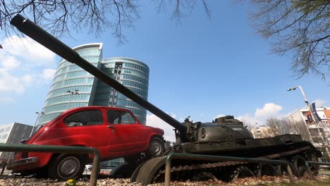 Old-car-and-tank-artistic-war-monument-with-a-blue-sky-background-Time-lapse-Static-Close-up-Low-angle-OSIJEK-,-CROATIA