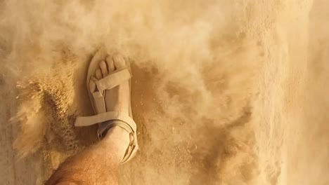 Closeup-Caucasian-man's-with-dusty-feet-walking-slow-motion-with-Sandals-On-Sandy-desert-or-Beach,-Footprints-Kicking-some-particles-sparkling-dust-sand-wearing-sandals-in-sunny-day
