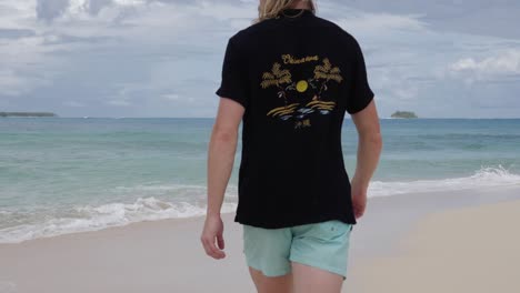 Young-blond-haired-caucasian-man-walking-away-from-camera-on-tropical-beach-in-Asia-in-ultra-slow-motion