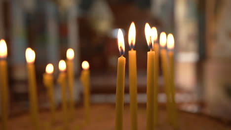 Medium-Shot-of-Thin-Yellow-Candle-Sticks-Burning-With-Lovely-Warm-Light-Inside-of-Madaba-St-George's-Greek-Orthodox-Church,-100-Frames-Per-Second