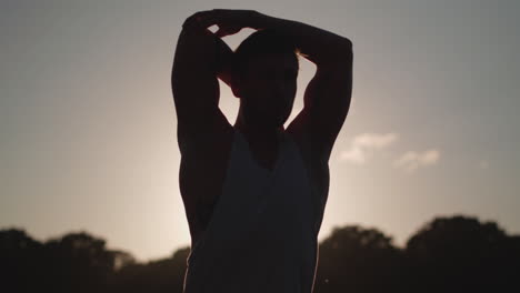Man-Stretches-Before-He-Works-Out-Whilst-Being-Silhouetted-By-The-Evening-Sun-In-Slow-Motion