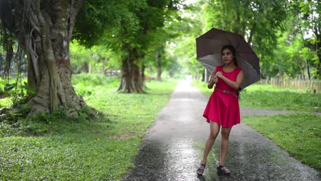 Ein-Wunderschönes-Romantisches-Mädchen-Rollt-Und-Spielt-Mit-Ihrem-Regenschirm-In-Der-Regenzeit-Auf-Der-Straße,-Zeitlupe