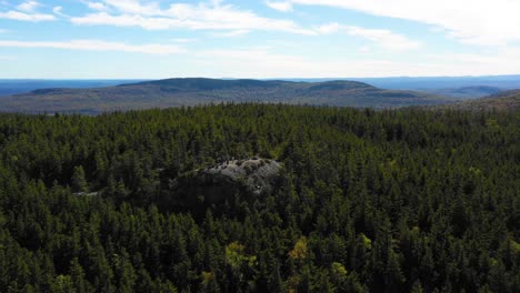 Aerial-drone-shot-pulling-back-from-a-group-of-people-hiking-and-standing-together-admiring-the-view-from-a-rocky-outcrop-in-the-Maine-wilderness