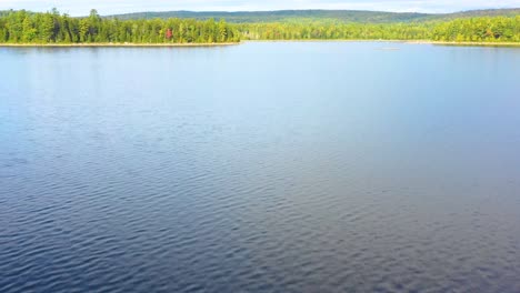 Luftaufnahmen-Im-Frühherbst-Eines-Abgelegenen-Sees-Im-Norden-Von-Maine,-Der-Tief-über-Das-Wasser-In-Richtung-Ufer-Fliegt